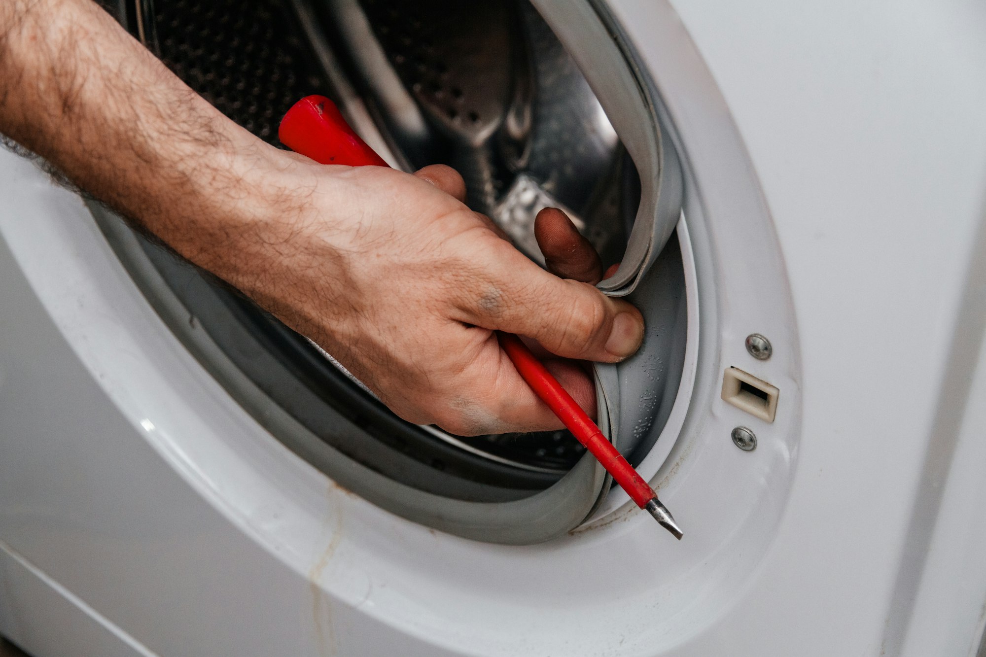 Handyman repairing a washing machine. The hands of a man repair a washing machine.