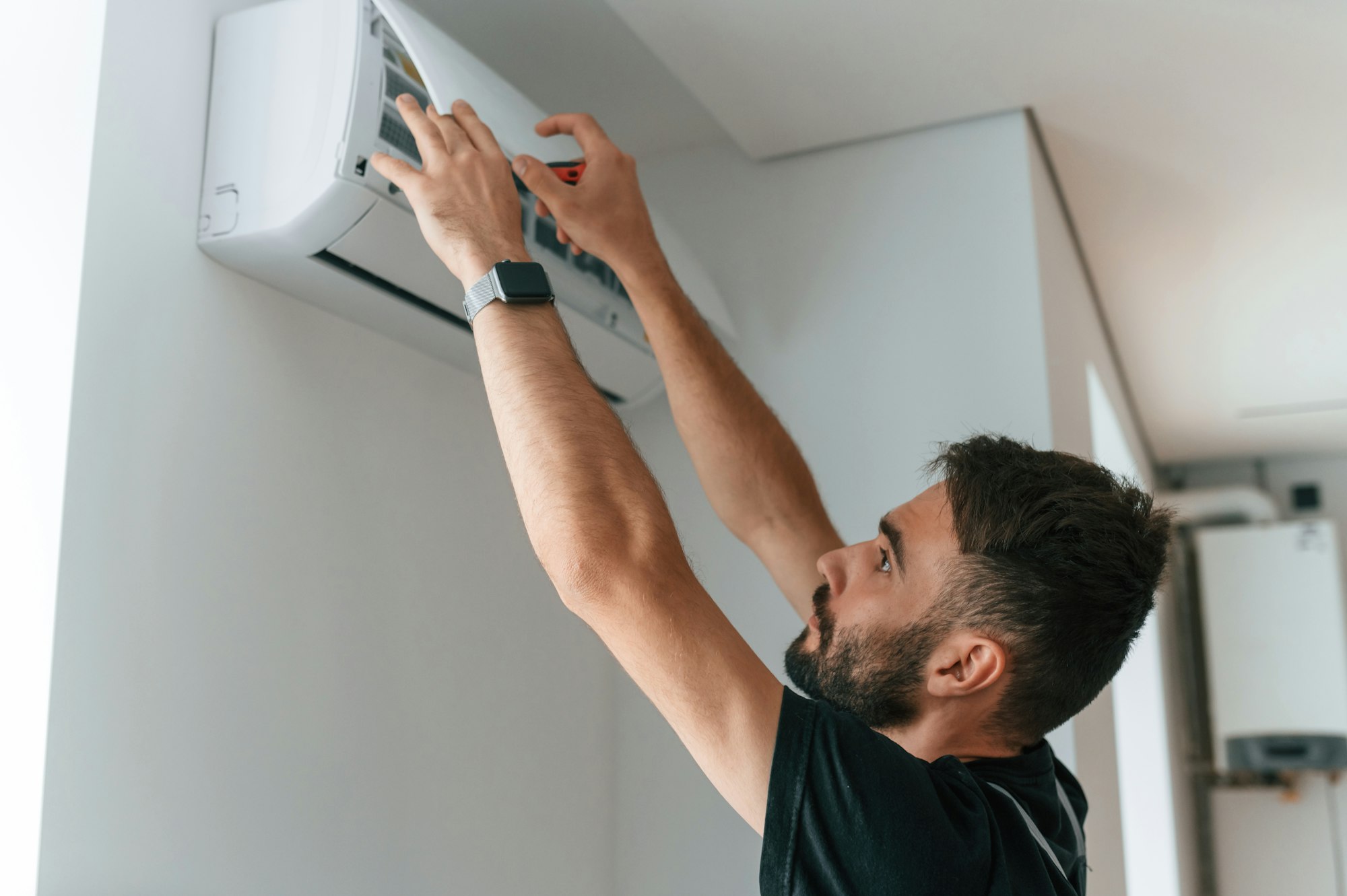 Man repairs an air conditioner indoors at home